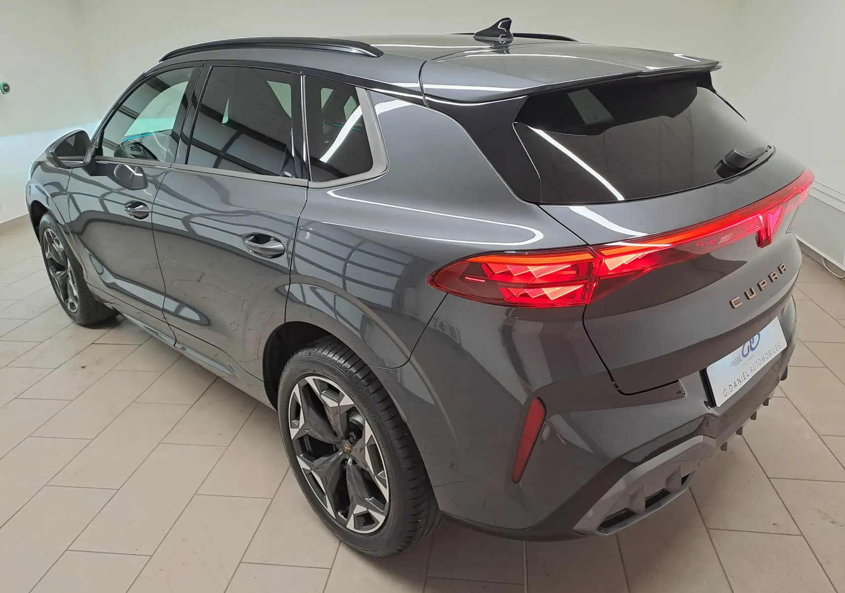 Vue 3/4 arrière droite du CUPRA TERRAMAR gris Timanfaya avec jantes 19'' Cosmic usinées et feux arrière allumés.