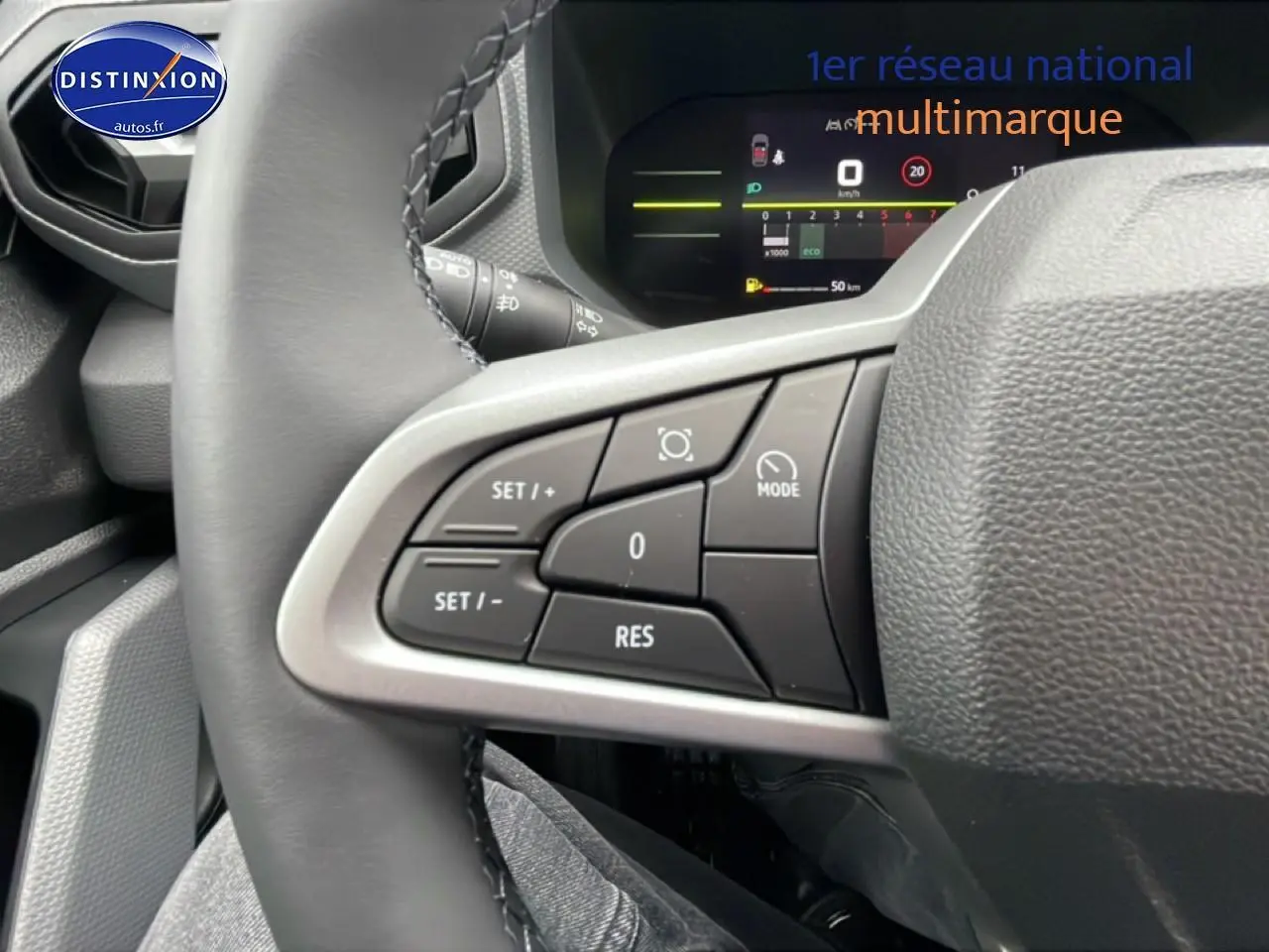 Gros plan sur les commandes au volant à gauche du Dacia Duster 2026, avec affichage numérique du tableau de bord en arrière-plan.