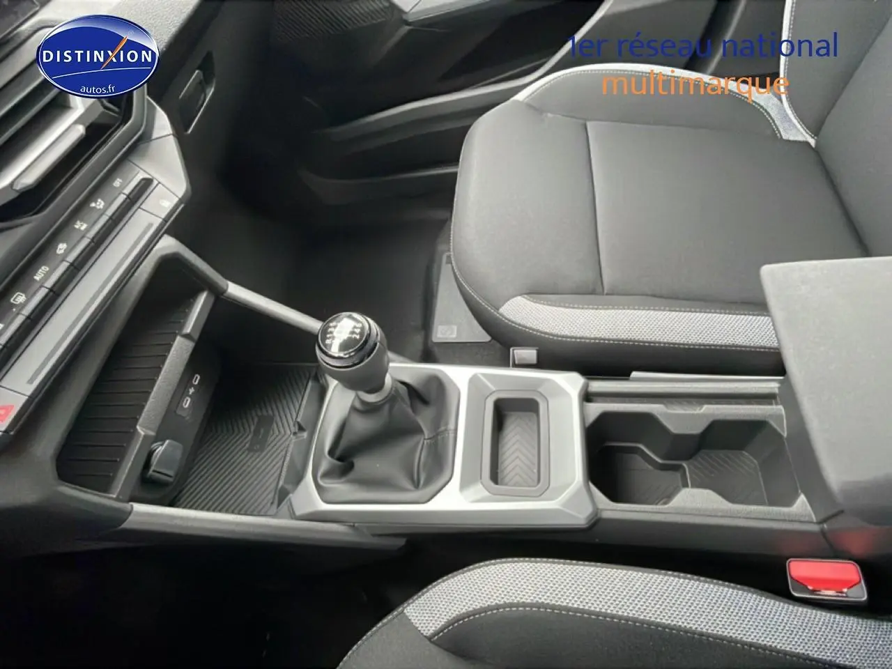 Vue intérieure centrée sur la console centrale et levier de vitesses manuelle du Dacia Duster 2026, sièges noirs.