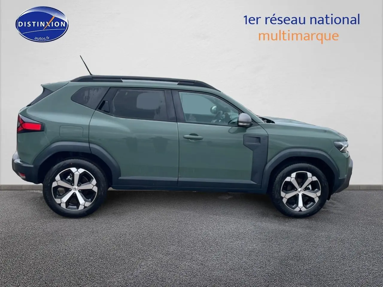 Vue de profil côté gauche d'un Dacia Duster 2026 vert kaki avec jantes alliage et barres de toit noires.