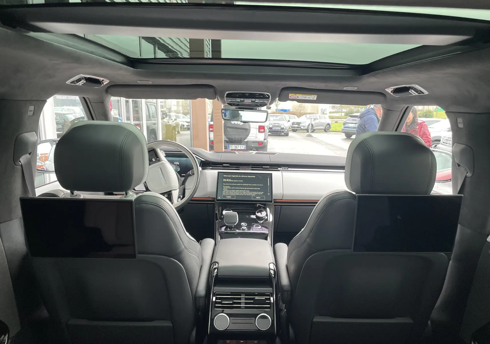 Vue intérieure arrière du Range Rover Sport P440 HSE R-Dynamic avec sièges cuir noirs et écrans intégrés aux appuie-têtes.