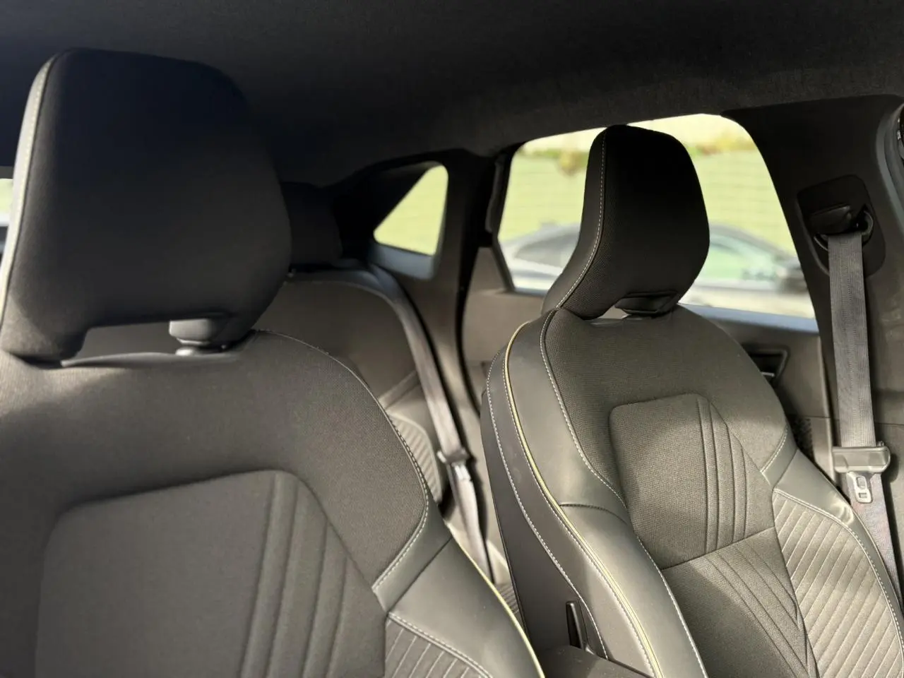Vue intérieure des sièges avant en tissu noir et cuir avec surpiqûres contrastantes du Renault Symbioz 2025.
