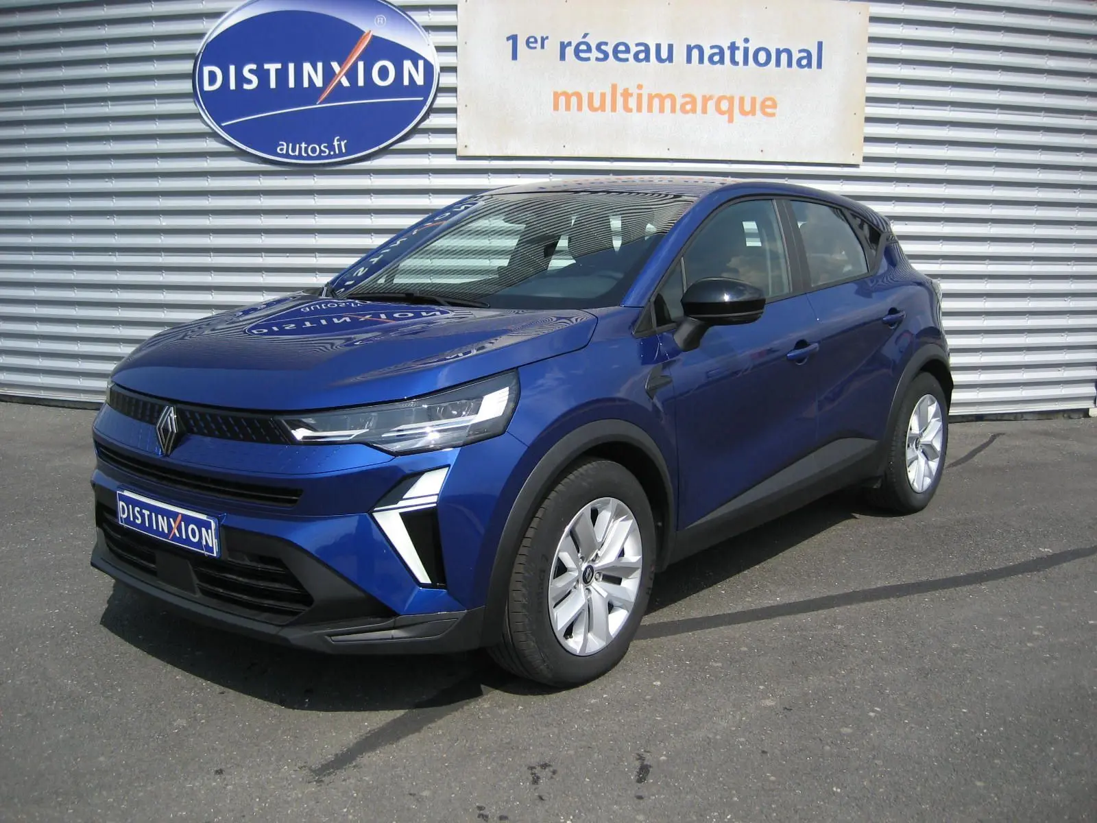Renault Captur II 1.6 E-Tech Hybride bleu Iron, vue 3/4 avant droit, avec calandre moderne et jantes argentées.