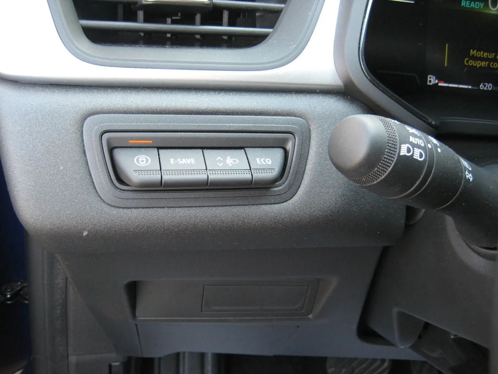 Gros plan sur les boutons de commande E-SAVE, ECO et éclairage à gauche du volant dans le Renault Captur II bleu Iron 2025.