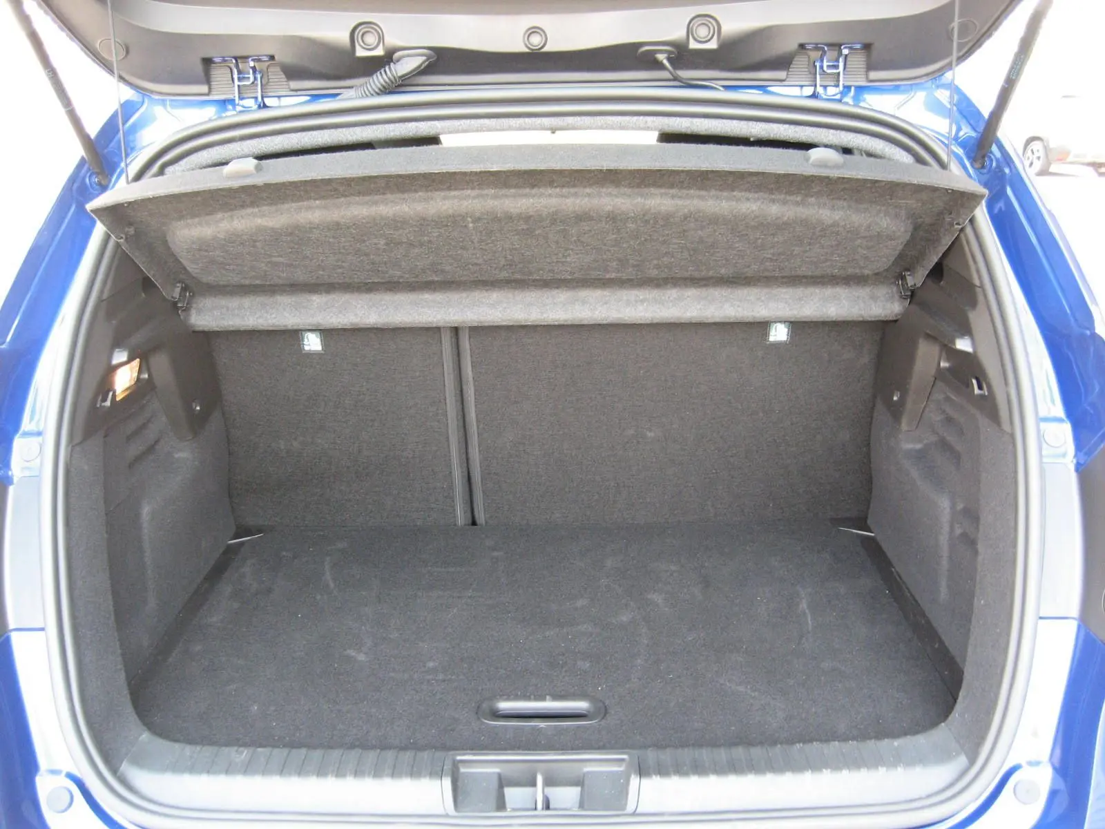 Coffre ouvert du Renault Captur II bleu iron, vue arrière montrant l’espace de rangement et la tablette cache-bagages relevée.