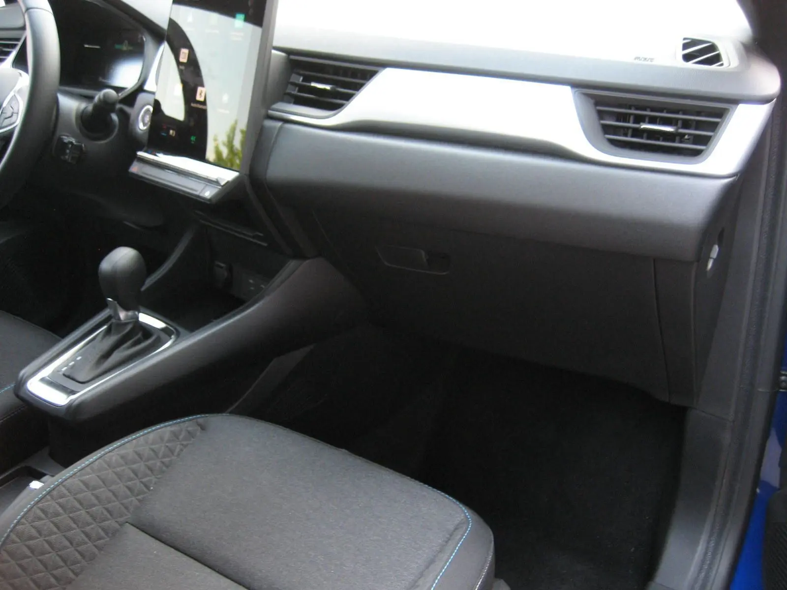 Vue intérieure côté passager du tableau de bord et console centrale du Renault Captur II bleu Iron avec boîte automatique.