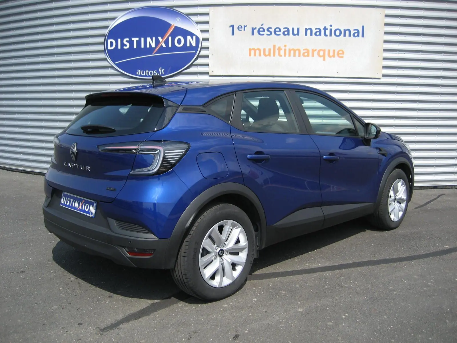 Renault Captur II 1.6 E-Tech hybride bleu Iron vu en 3/4 arrière droit, avec feux arrière LED et jantes alliage.