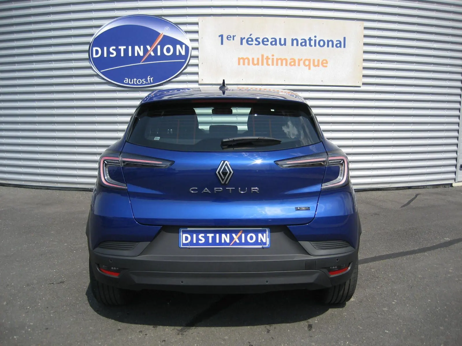 Vue arrière d'un Renault Captur II bleu iron 2025 avec feux LED et logo distinctif sur un parking extérieur.
