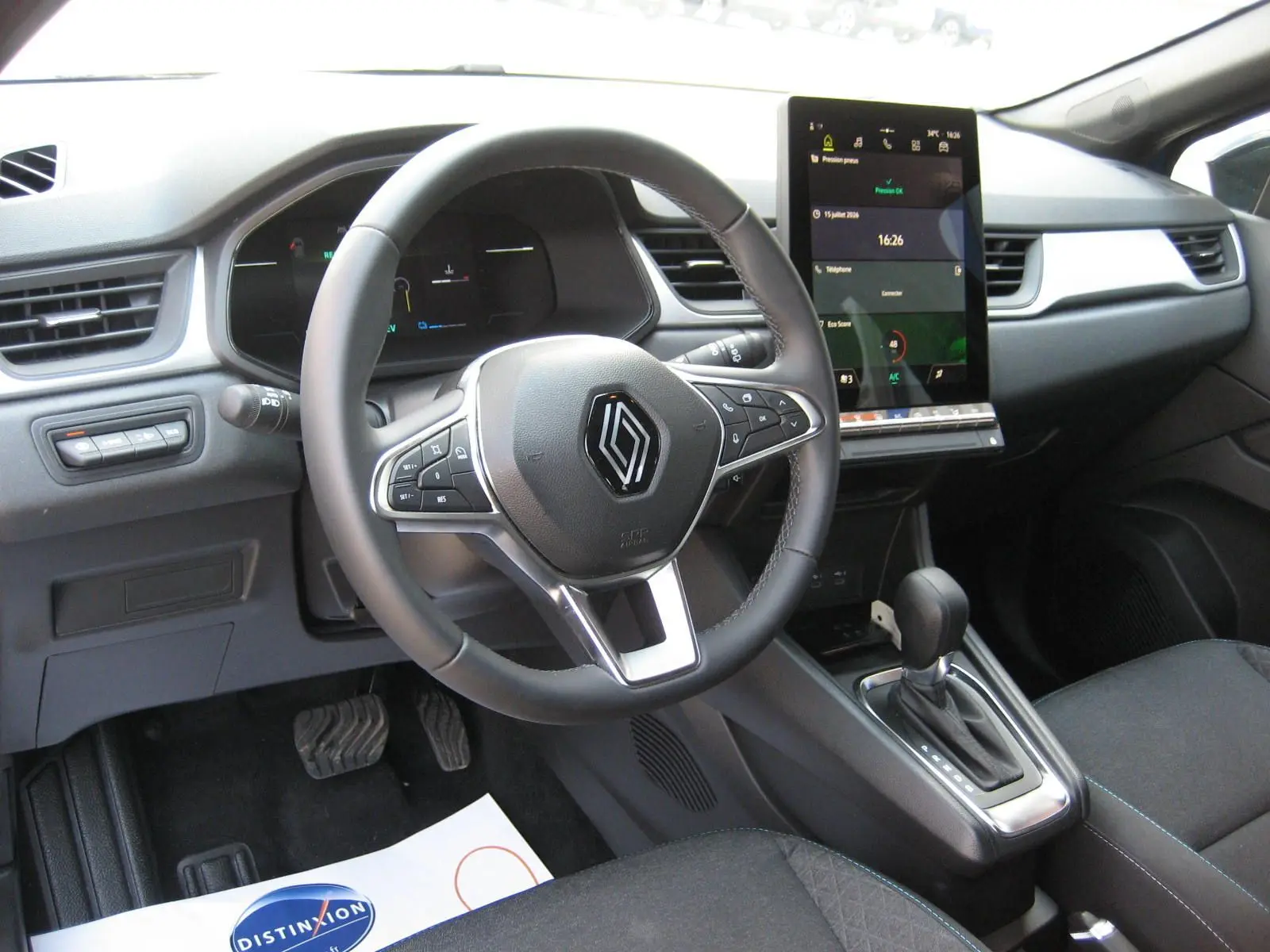 Vue intérieure du tableau de bord et volant du Renault Captur II hybride 2025, avec écran tactile vertical et levier de boîte automatique.