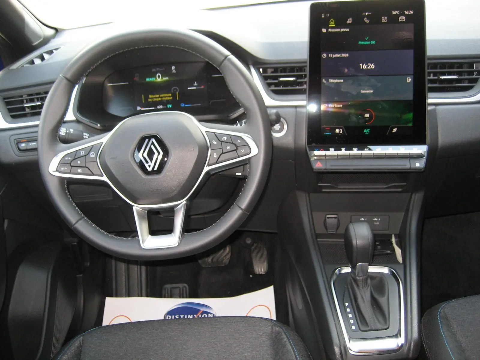 Vue intérieure frontale du tableau de bord du Renault Captur II bleu Iron, avec volant multifonction et écran tactile central allumé.