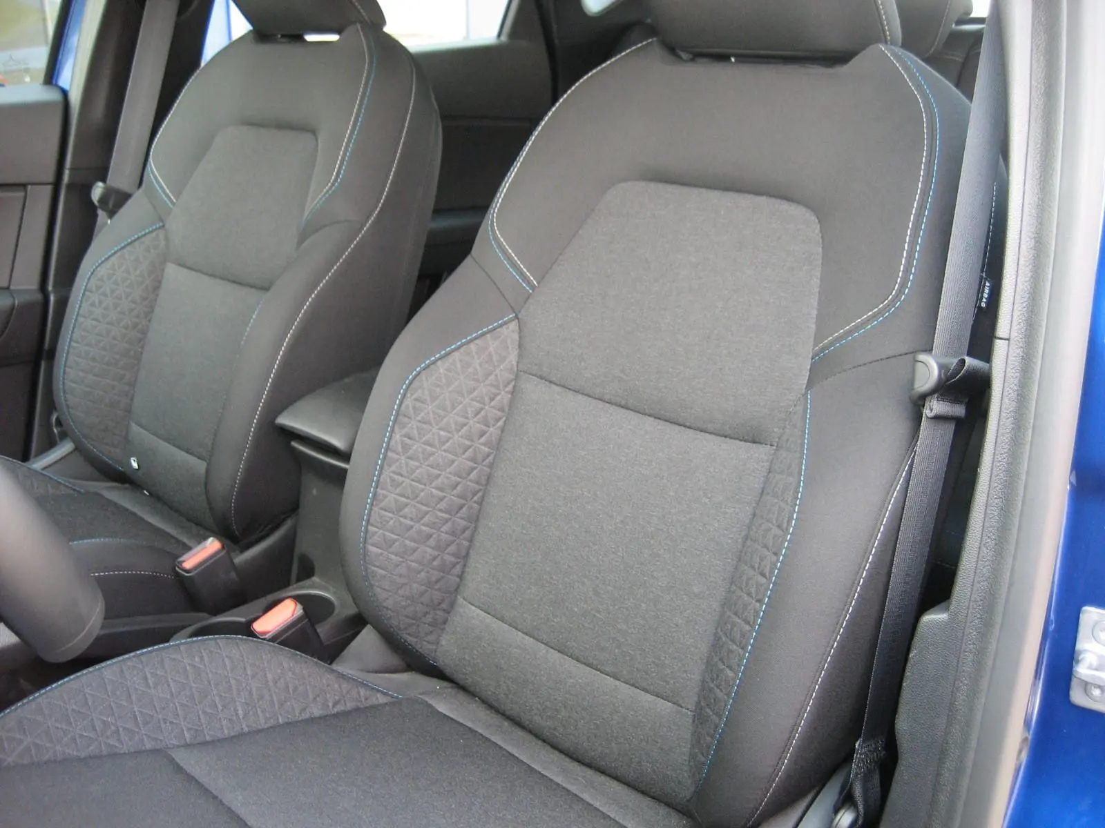 Vue rapprochée des sièges avant gris avec surpiqûres bleues du Renault Captur II 1.6 E-Tech Hybride 2025 bleu Iron.