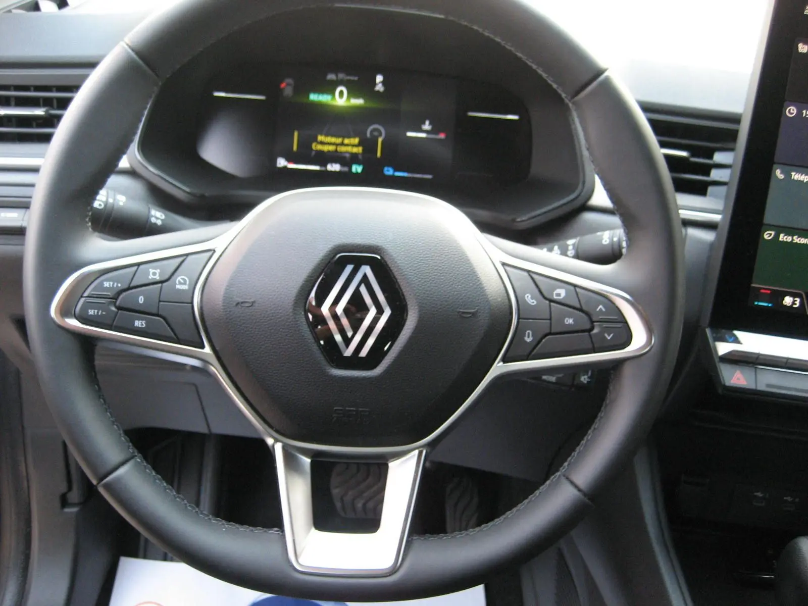 Vue rapprochée du volant noir du Renault Captur II 1.6 E-Tech Hybride 2025 avec tableau de bord numérique allumé.