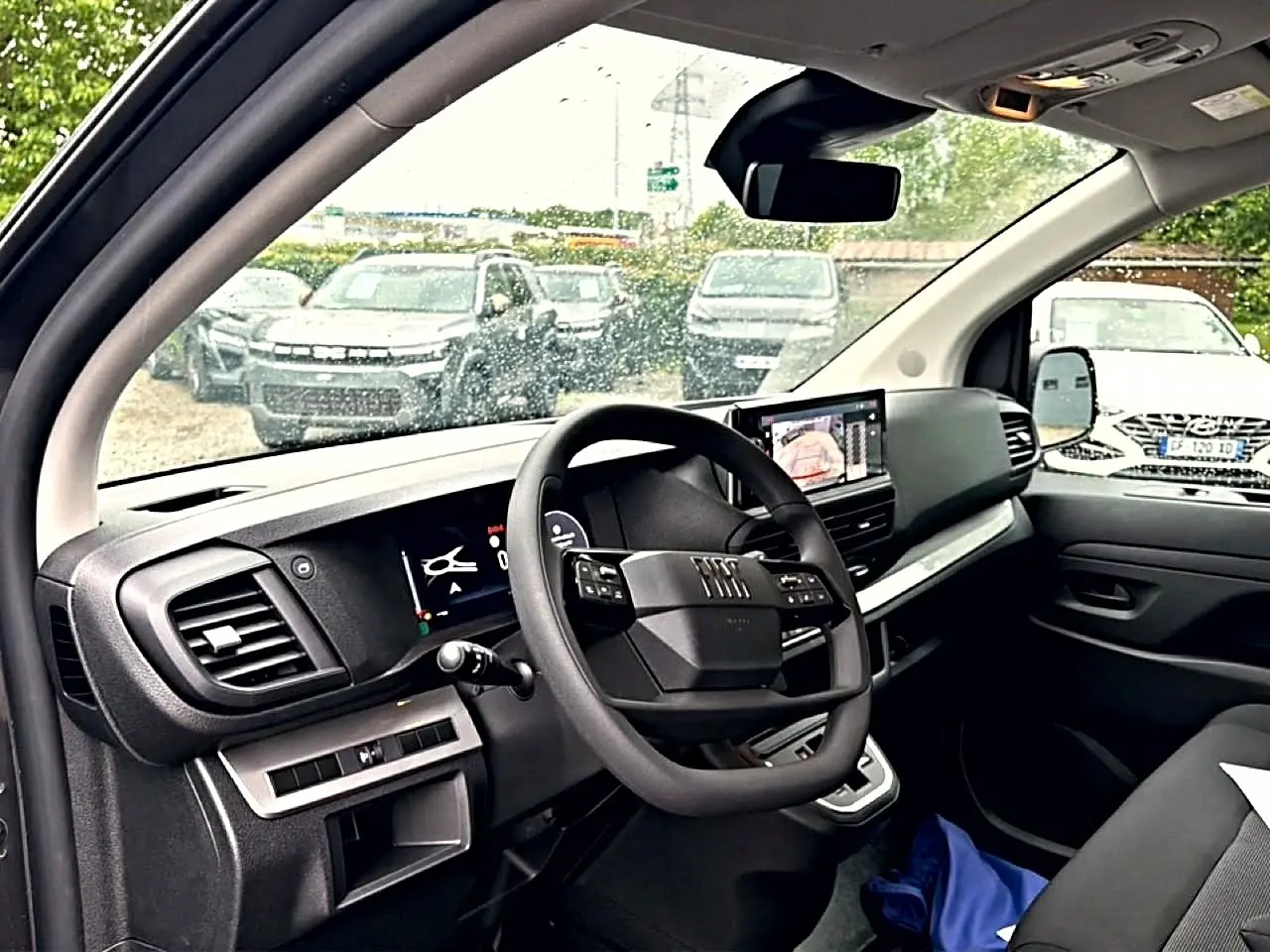 Vue intérieure côté conducteur du Fiat Scudo Combi gris titane, avec tableau de bord moderne et écran tactile central.