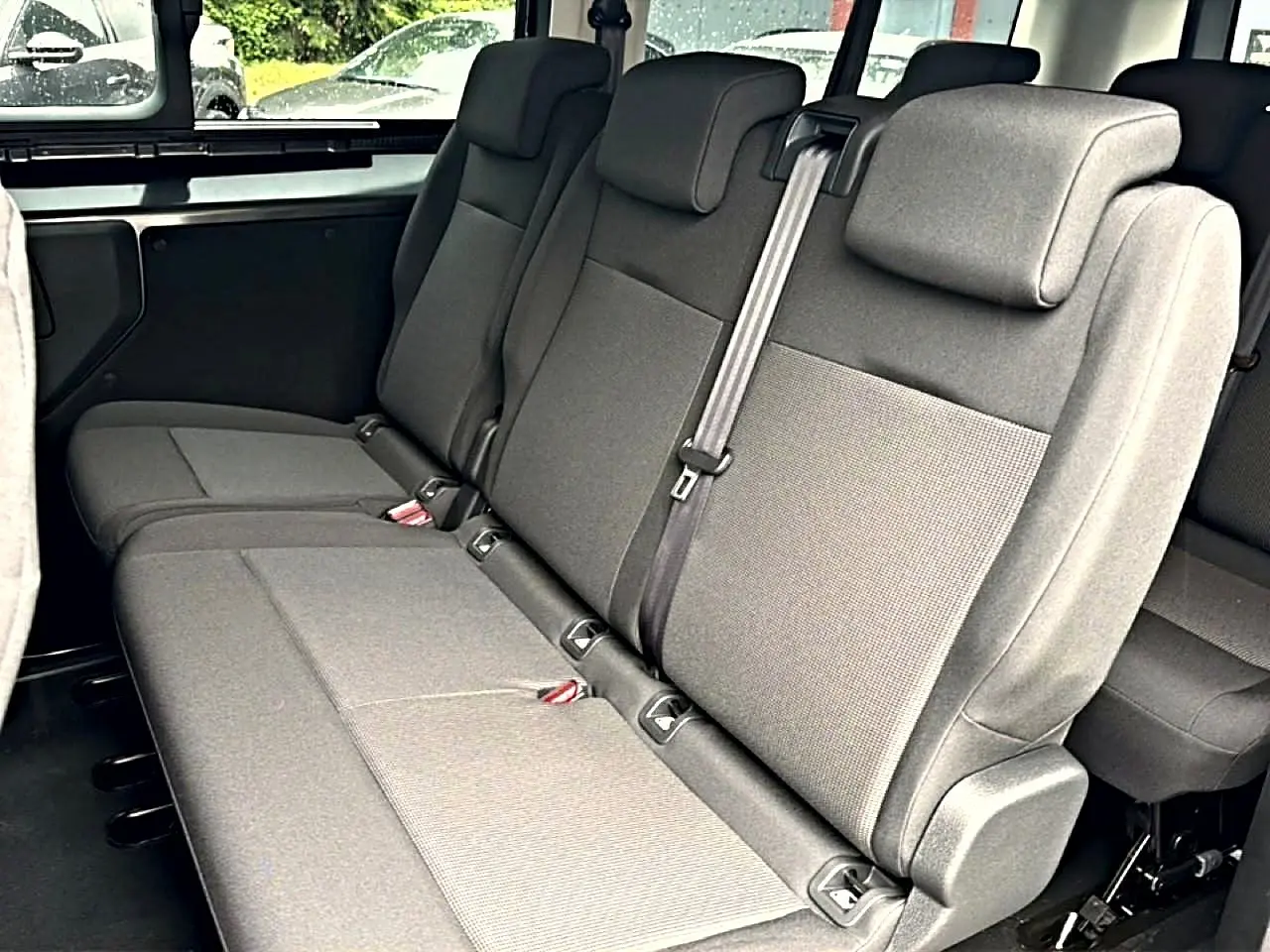 Vue intérieure sur la banquette arrière 3 places gris foncé du Fiat Scudo Combi XL 2026 avec appuie-têtes et ceinture centrale.
