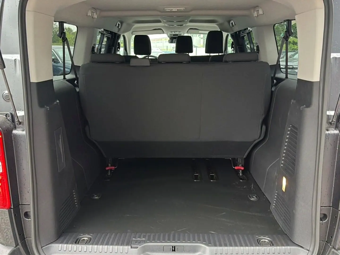 Vue arrière du coffre ouvert du FIAT Scudo Combi gris titane, montrant la banquette arrière et l’espace de chargement.