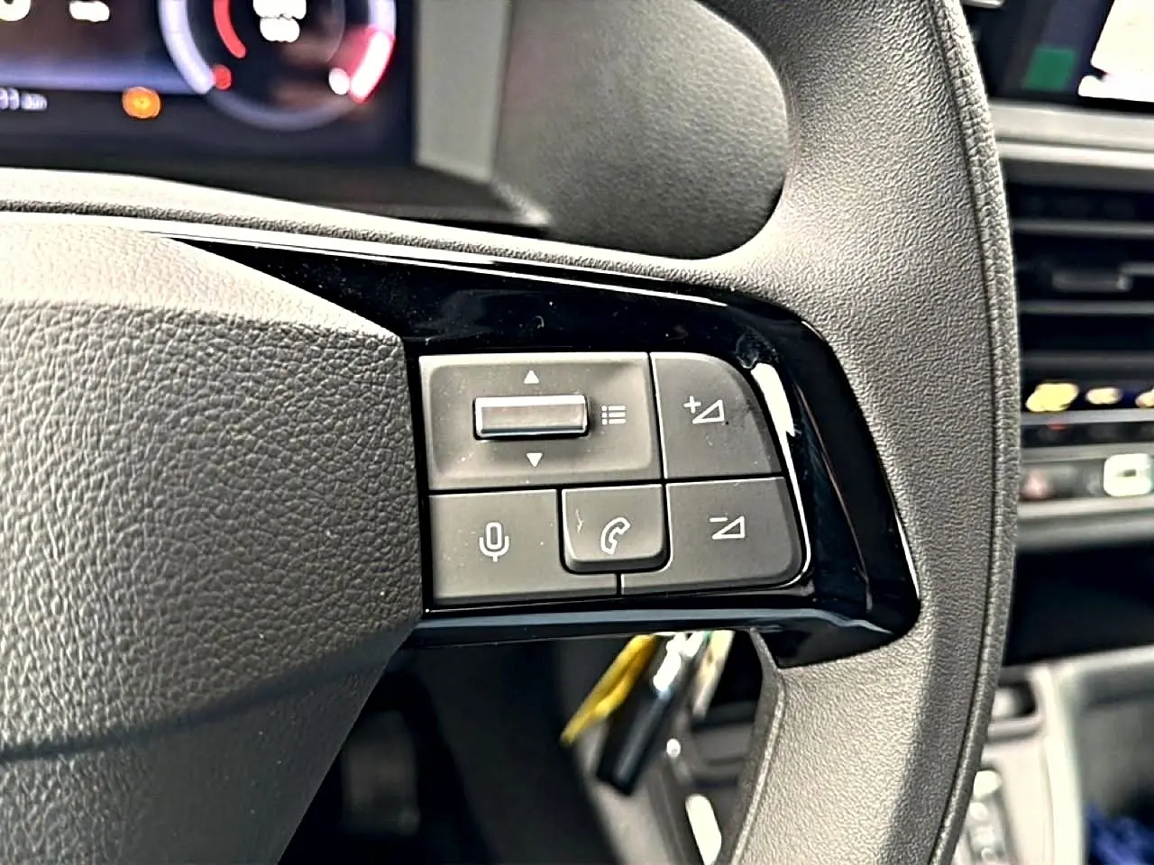 Gros plan sur les commandes au volant noir du Fiat Scudo Combi gris titane, avec écran multifonction en arrière-plan.