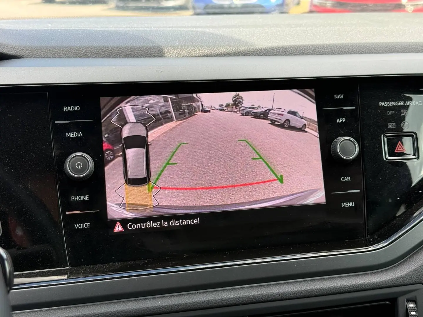 Affichage caméra de recul du Volkswagen Taigo gris, vue arrière avec lignes de guidage vertes et rouges sur écran tactile.