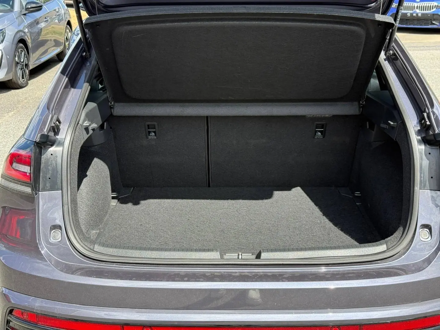 Coffre ouvert vu de l'arrière d'un Volkswagen Taigo gris, montrant l'espace de chargement et la tablette cache-bagages.