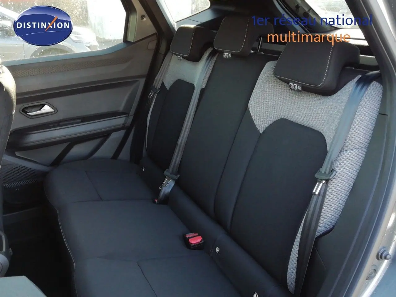 Vue intérieure arrière du Dacia Duster 2026, sièges tissu noir et gris avec ceintures de sécurité visibles.