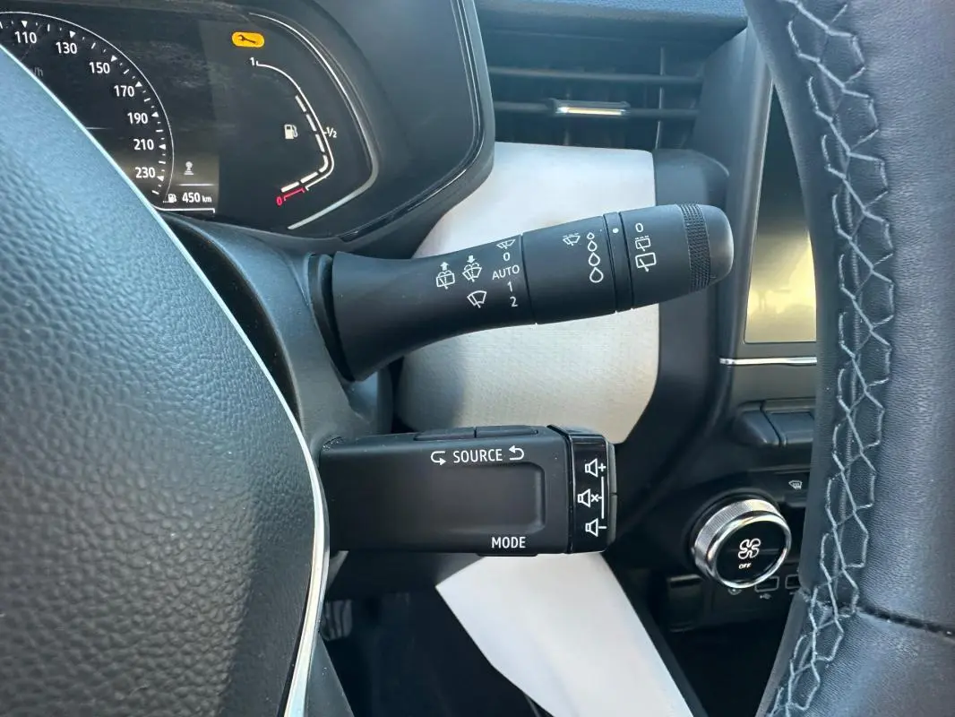 Vue rapprochée du commodo de commandes au volant d'une Renault Clio rouge foncé, version Intens 2021.