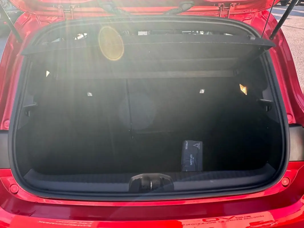 Coffre ouvert d'une Renault Clio rouge foncé 2021, vue arrière, montrant un espace de rangement propre et un kit de sécurité.