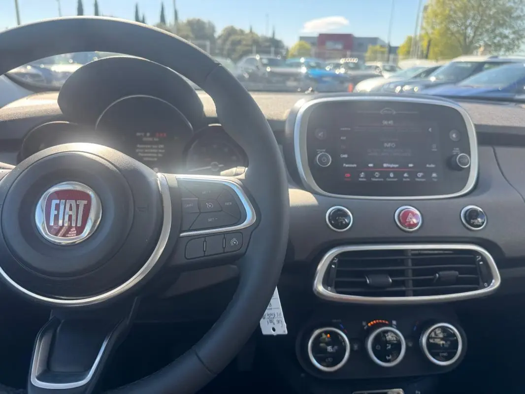 Vue intérieure du tableau de bord et volant FIAT 500X MY23, avec écran tactile et commandes au volant visibles.