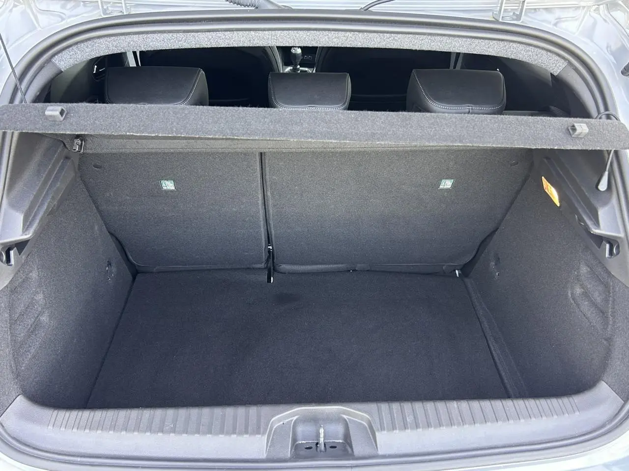 Coffre ouvert de la Renault Clio V TCE 90 Techno gris Rafale, montrant l’espace de chargement vide et les dossiers arrière.