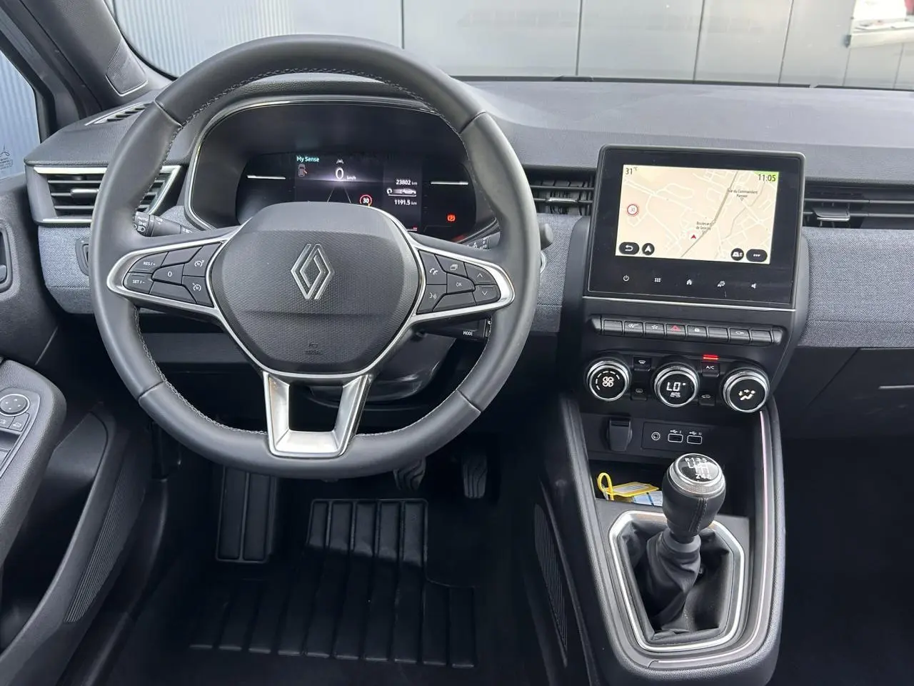 Vue intérieure centrée sur le volant multifonction et la console centrale avec écran tactile de la Renault Clio Gris Rafale.