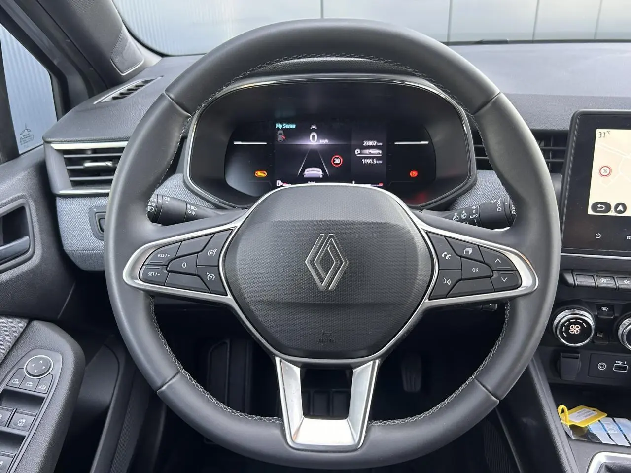 Vue rapprochée du volant multifonction noir et du tableau de bord numérique de la Renault Clio 2025.