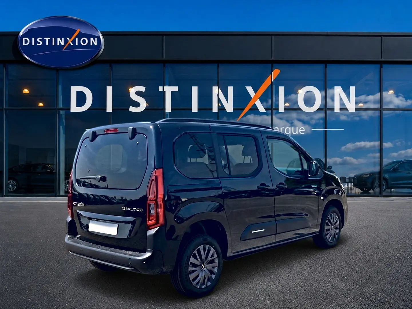 Vue 3/4 arrière droite du Citroën Berlingo noir stationné devant une vitrine avec logo Distinxion.