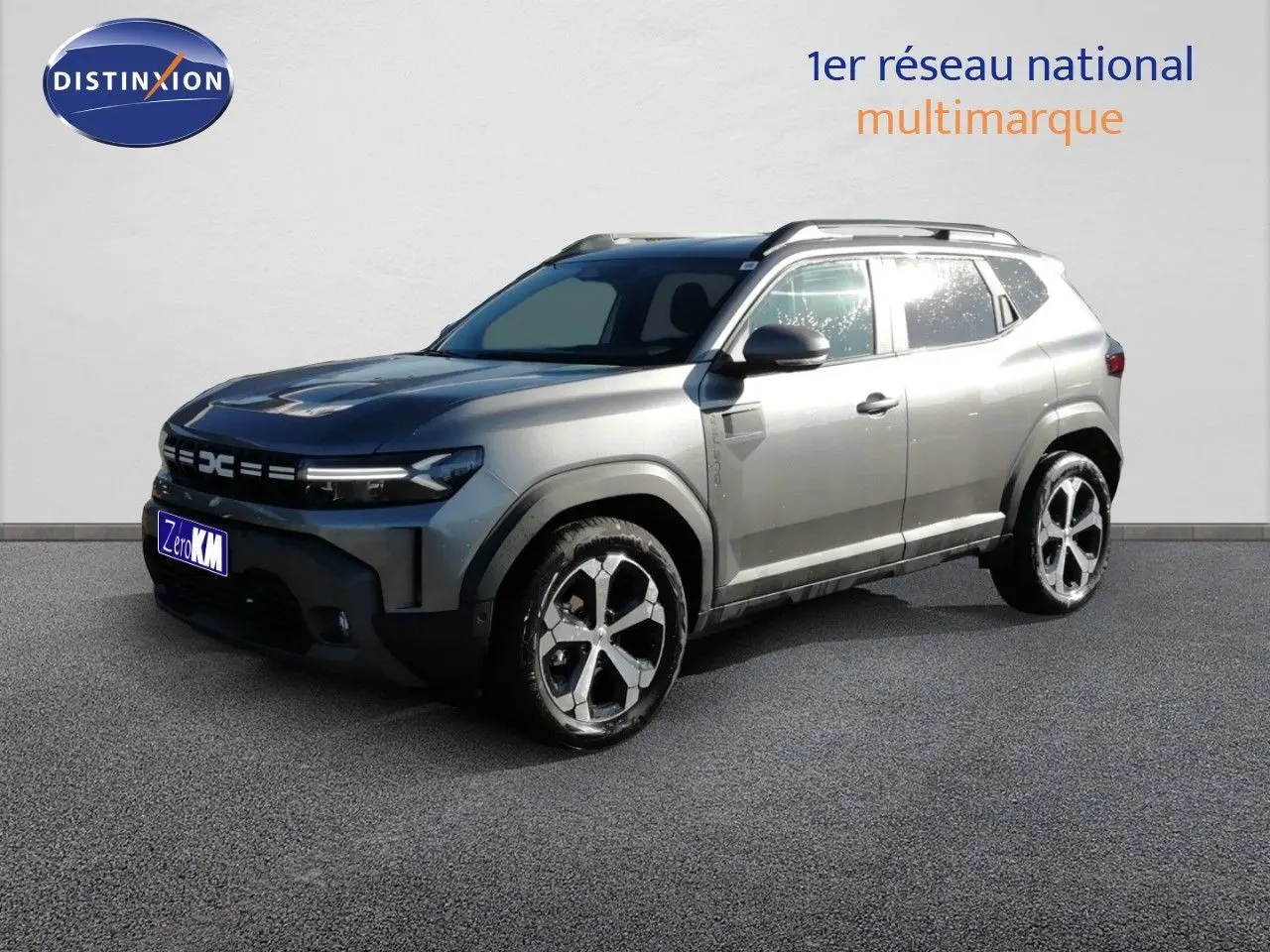 SUV Dacia Duster gris schiste métal en 3/4 avant droit, avec jantes alliage bicolores et barres de toit.