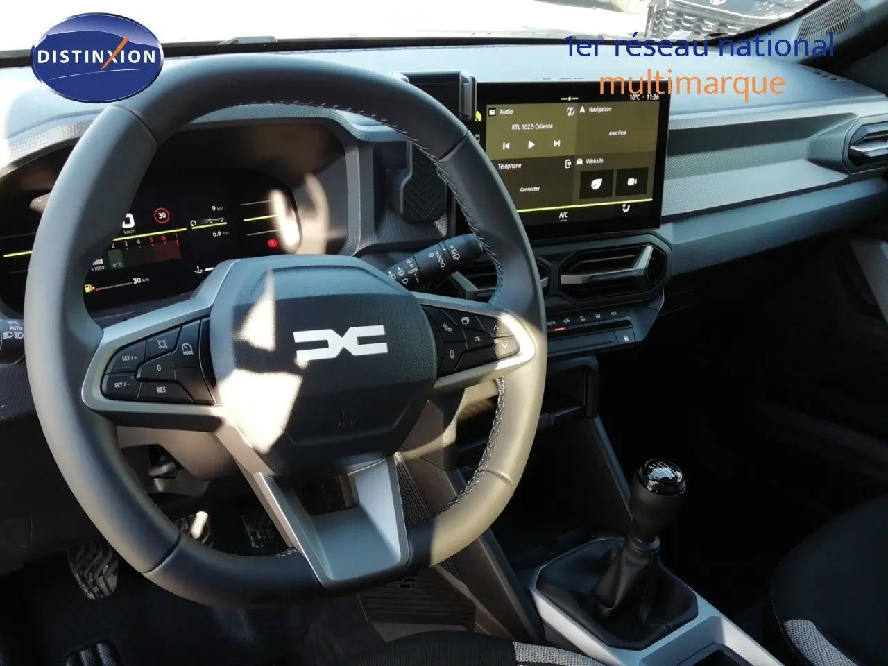 Vue intérieure du tableau de bord du Dacia Duster 2026, volant multifonction et écran tactile central visibles.