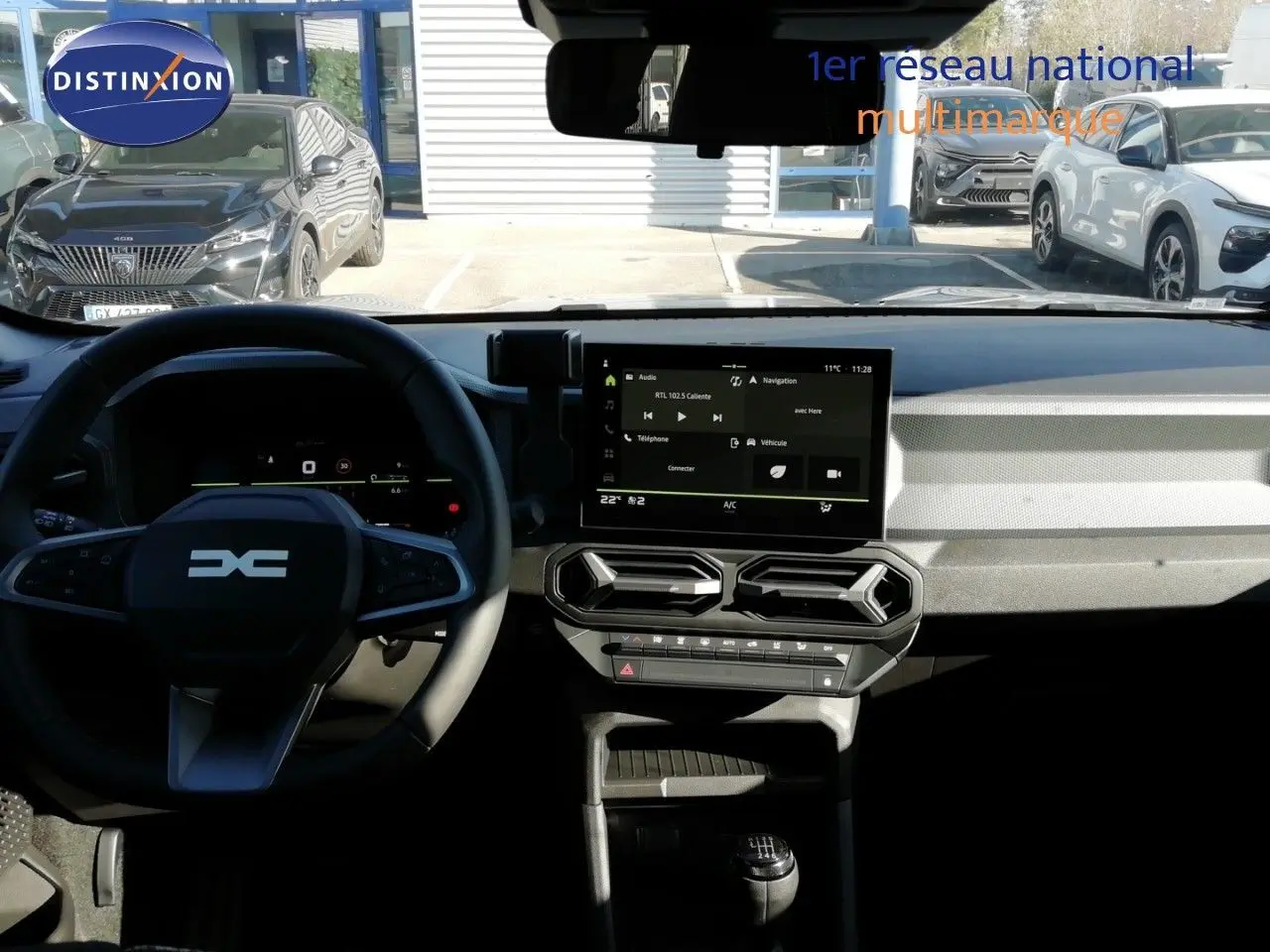 Vue intérieure du tableau de bord et volant du Dacia Duster 2026, avec écran tactile central et levier de vitesses manuel.