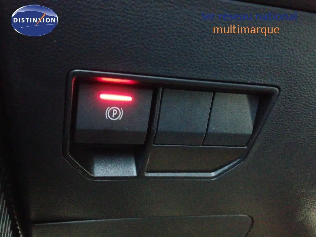 Gros plan sur le bouton de frein à main électrique allumé dans l’habitacle du Dacia Duster gris schiste métal 2026.