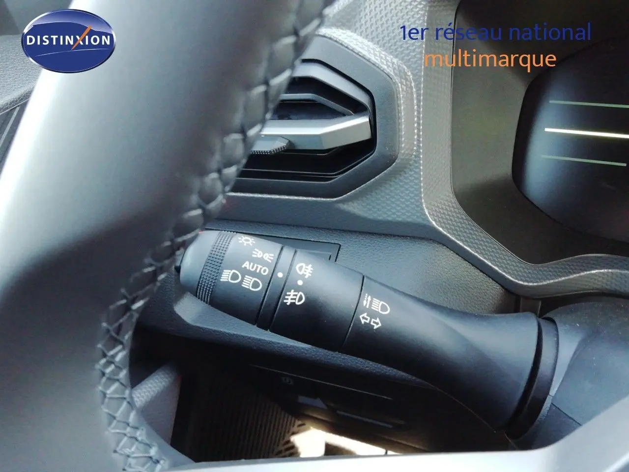 Gros plan sur la commande des phares côté gauche du volant dans l’habitacle gris noir du Dacia Duster 2026.