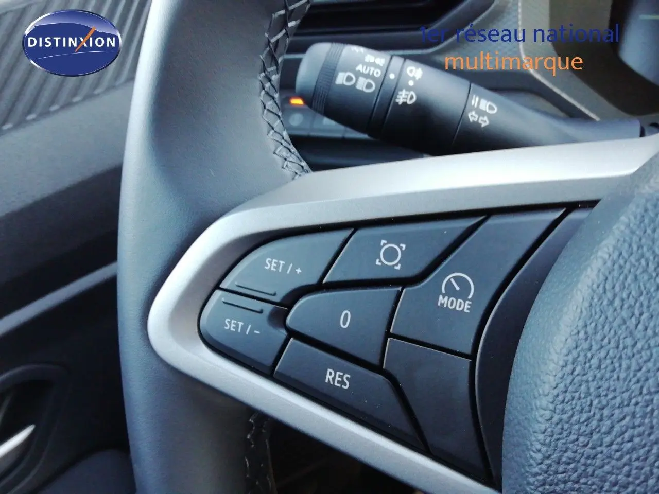 Gros plan sur les commandes au volant à gauche du Dacia Duster gris schiste métal, avec boutons de régulateur de vitesse.