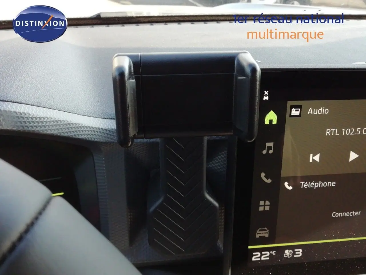 Support téléphone fixé sur la planche de bord du Dacia Duster gris schiste, avec écran tactile affichant la radio et la climatisation.