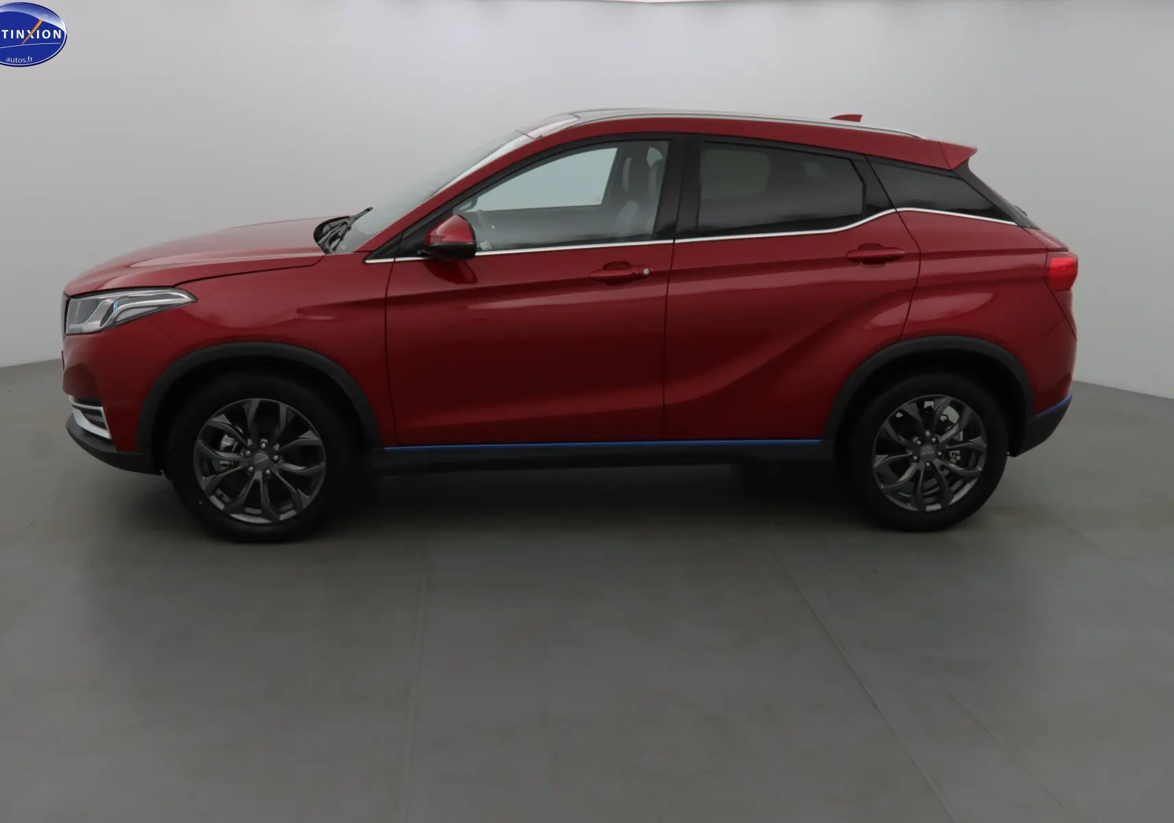 Vue de profil côté gauche du SUV électrique SERES 3 rouge solaire métal avec jantes alliage et lignes dynamiques.