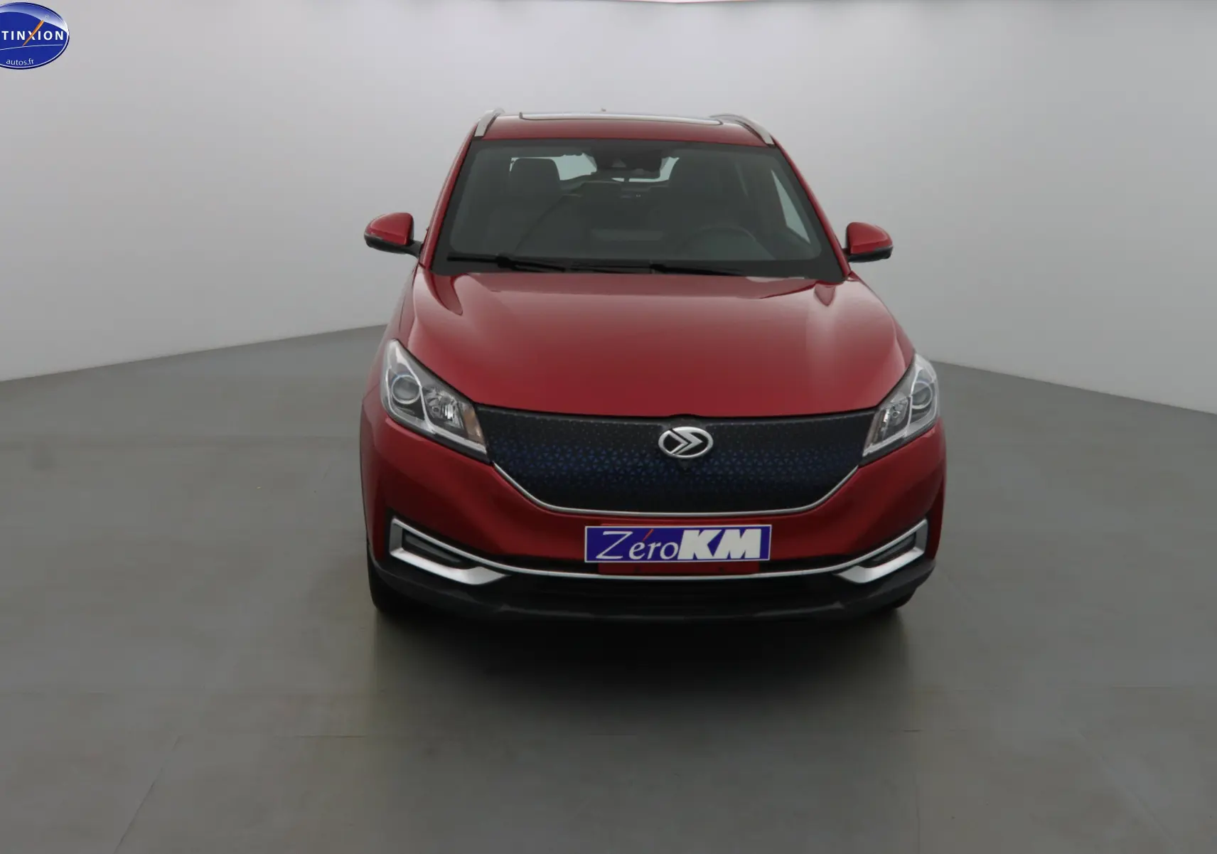 Vue frontale d'un SUV SERES 3 rouge solaire métal avec calandre noire et plaque "Zéro KM" visible.