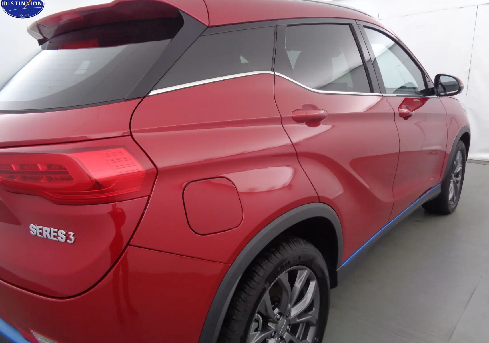 Vue 3/4 arrière droite du SUV électrique SERES 3 rouge solaire métallisé avec jantes alliage et vitres teintées.