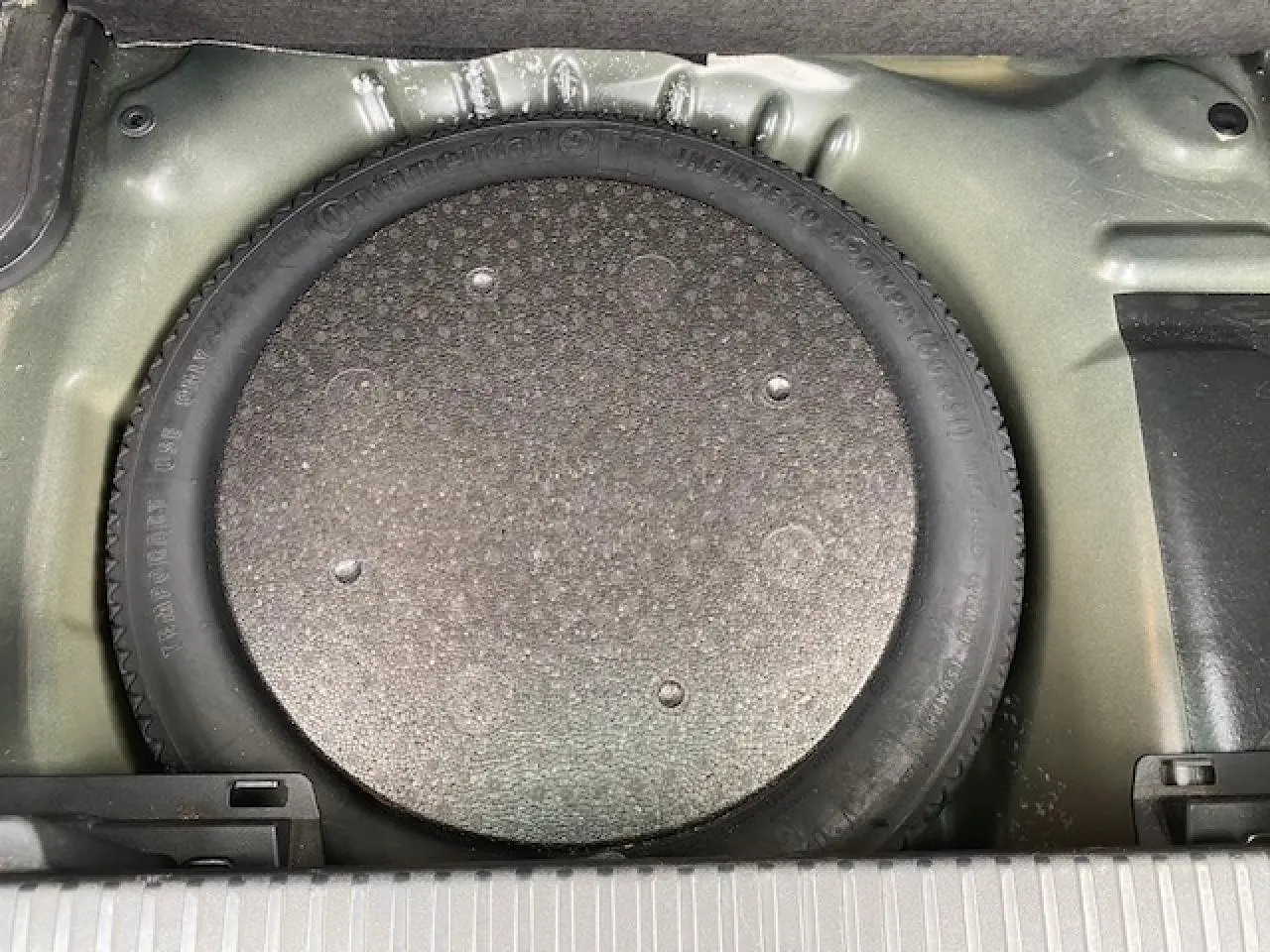 Vue plongeante sur la roue de secours galette dans le coffre d'un Citroën C3 Aircross noir 2019.