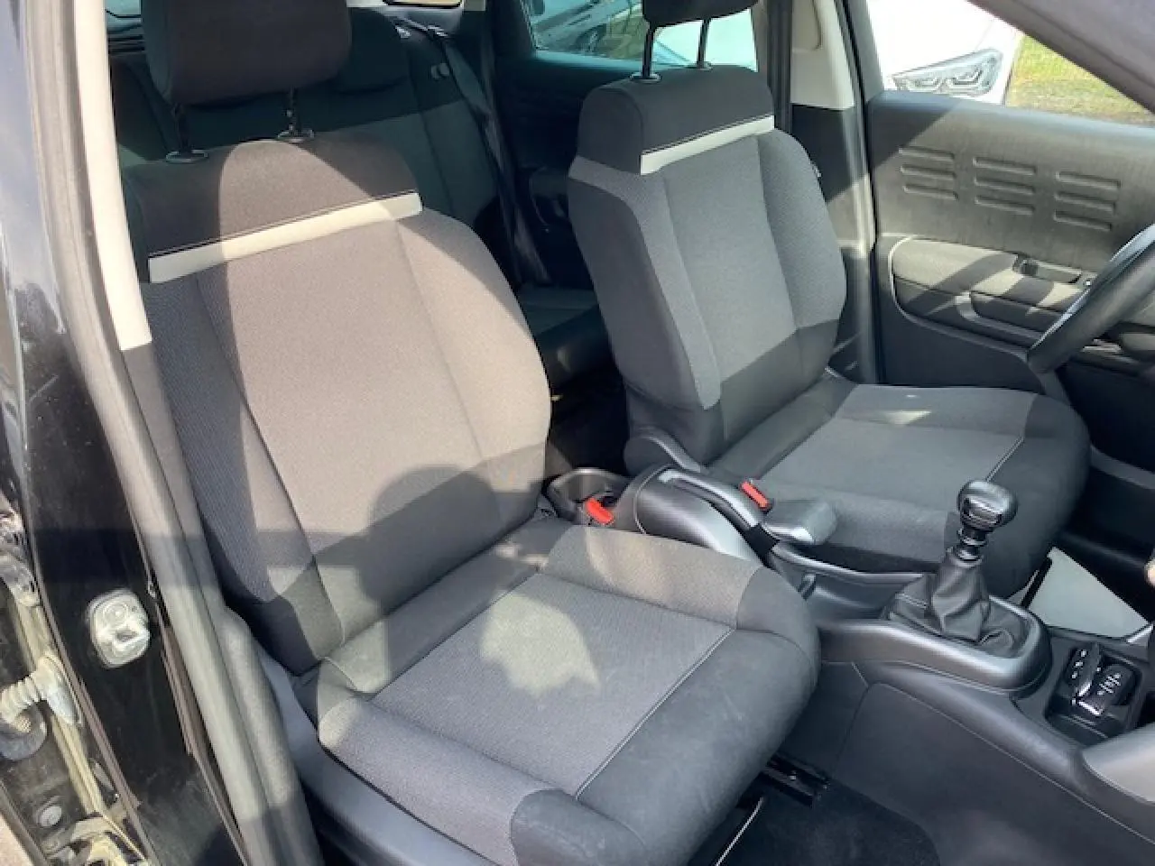 Intérieur avant du Citroën C3 Aircross noir 2019, vue côté gauche sur sièges tissu gris et levier de vitesse manuel.