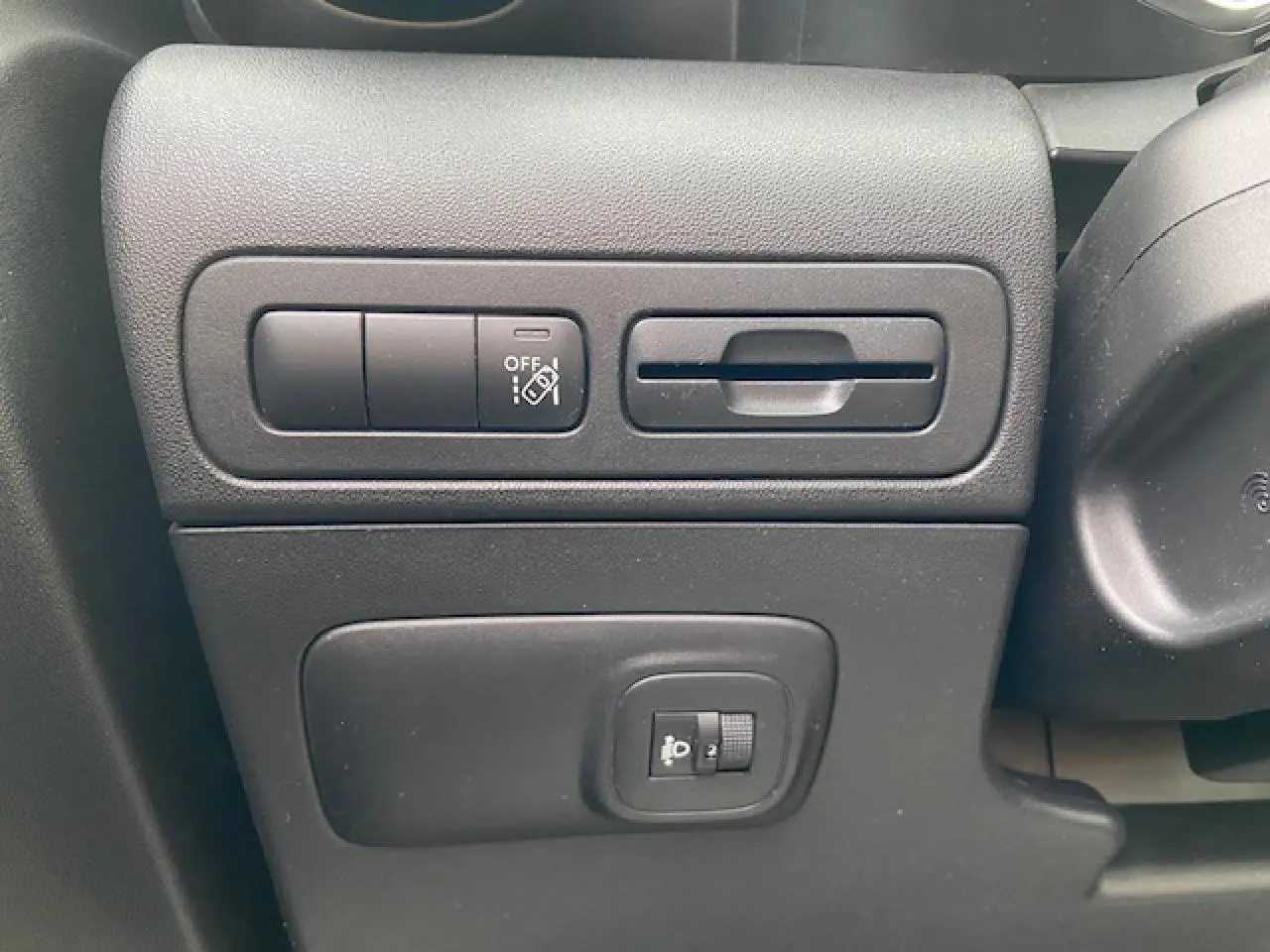 Vue rapprochée des commandes de réglage des phares et des aides à la conduite sur le tableau de bord noir du Citroën C3 Aircross.
