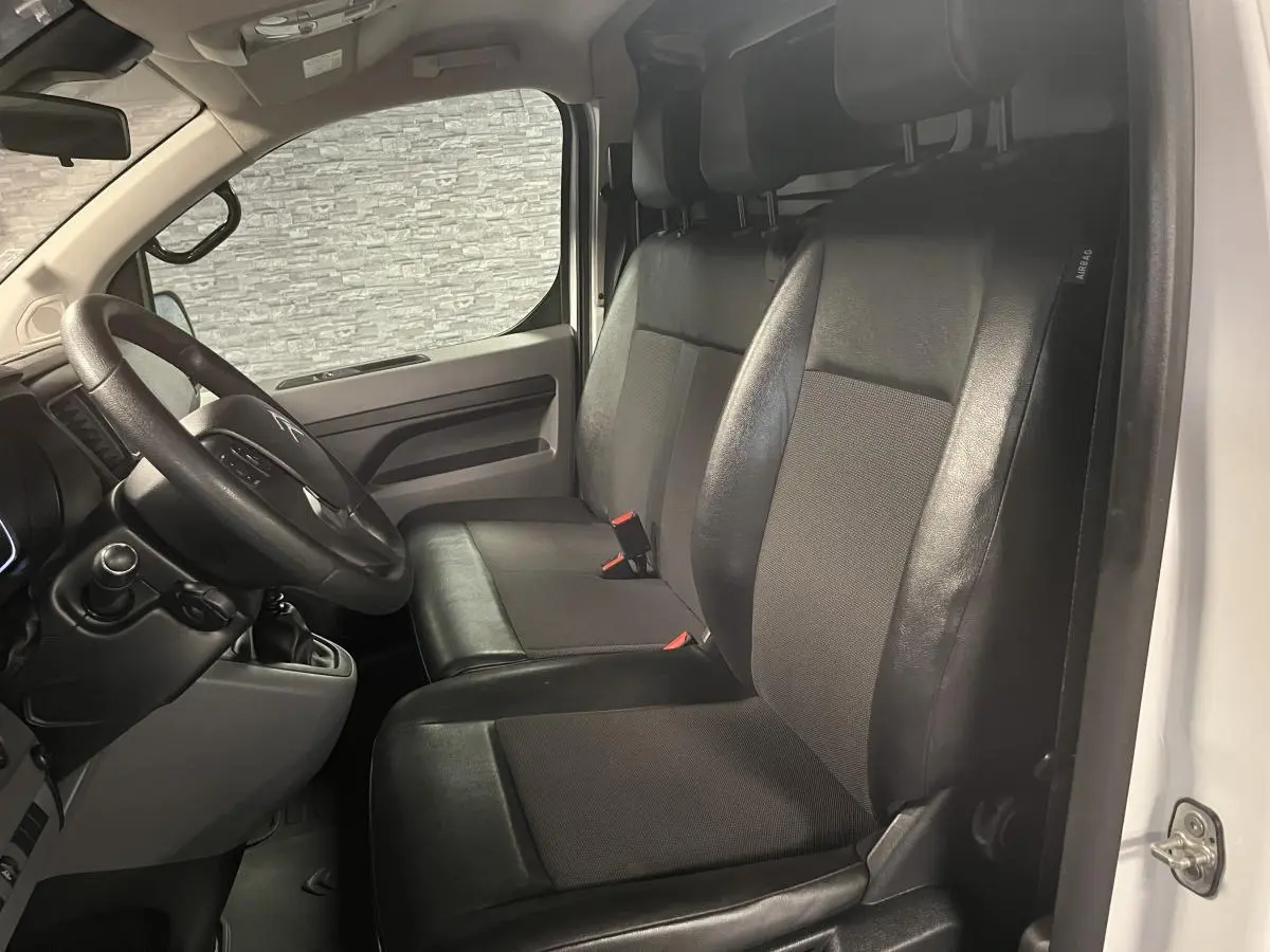 Vue intérieure côté conducteur du Citroën Jumpy blanc 2019 avec sièges mixtes TEP/tissu et volant noir.