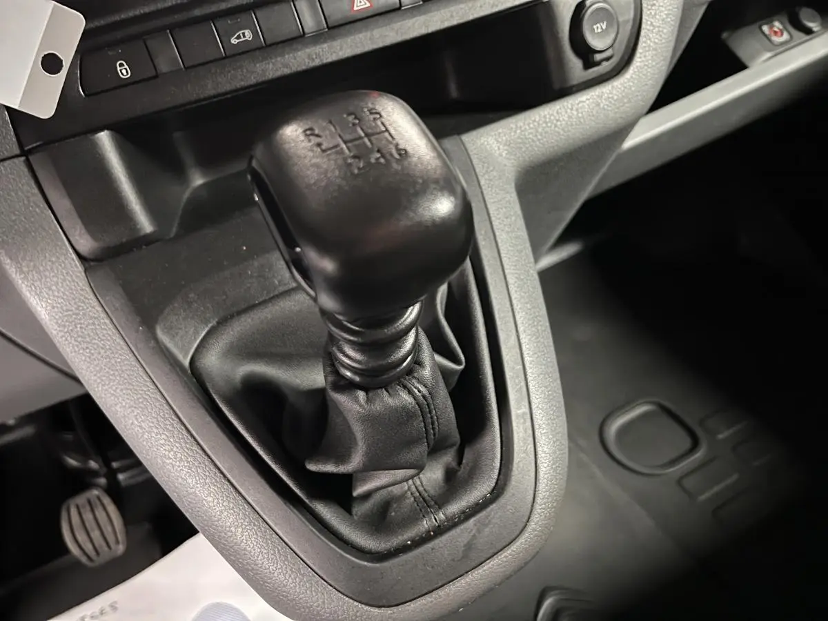 Gros plan sur levier de vitesses manuel noir dans l'habitacle gris du Citroën Jumpy blanc de 2019.