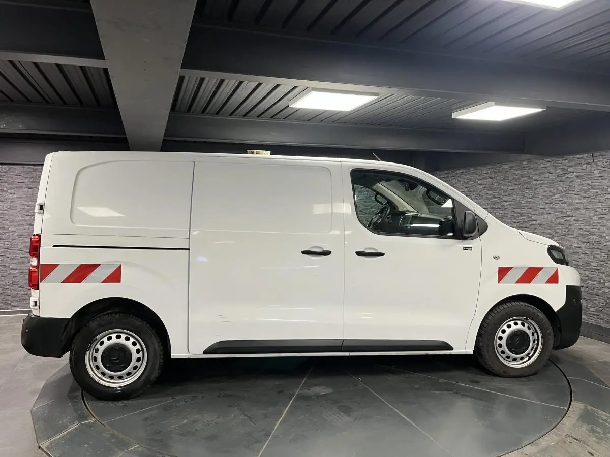 Profil droit d'un utilitaire Citroën Jumpy blanc de 2019 avec bandes réfléchissantes rouges et blanches sur ailes avant et arrière.