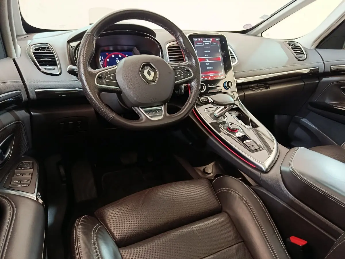 Intérieur noir du Renault Espace 2018 vu côté conducteur, volant cuir, écran tactile vertical et console centrale éclairée rouge.