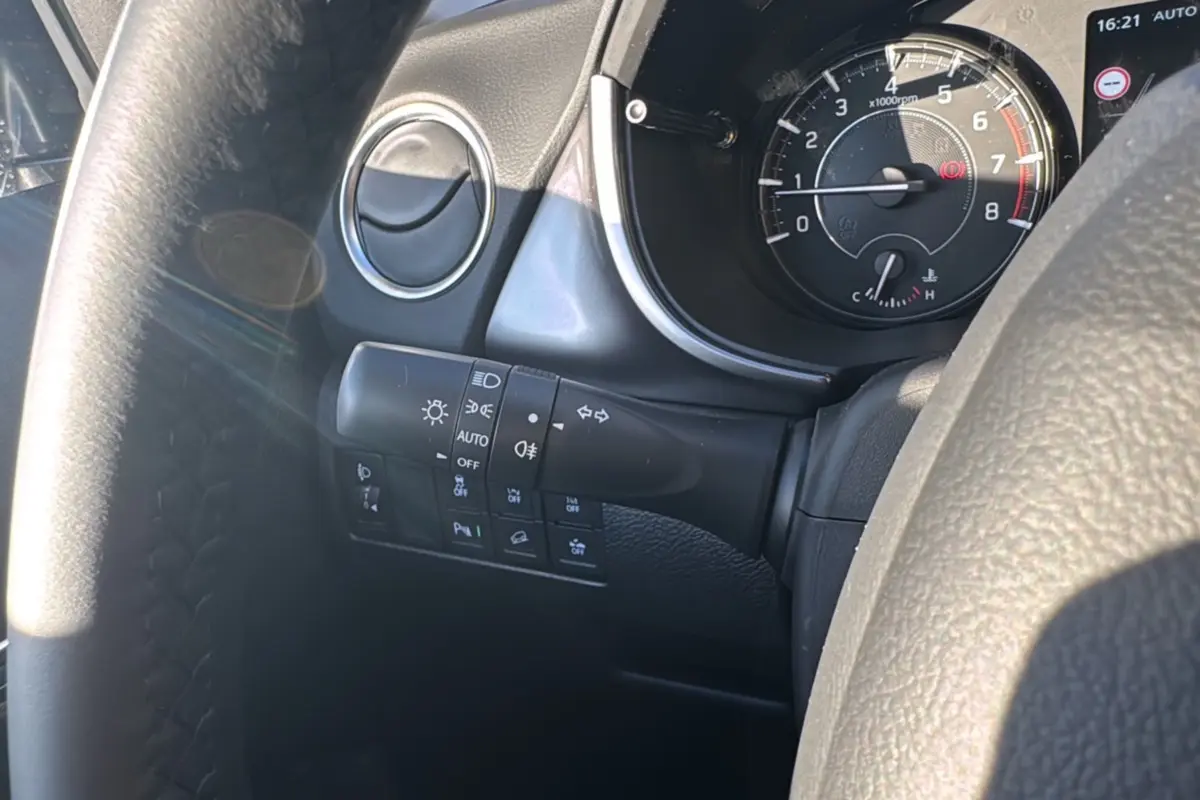 Gros plan sur le tableau de bord et la commande des phares du Suzuki Vitara 2025 en intérieur noir.