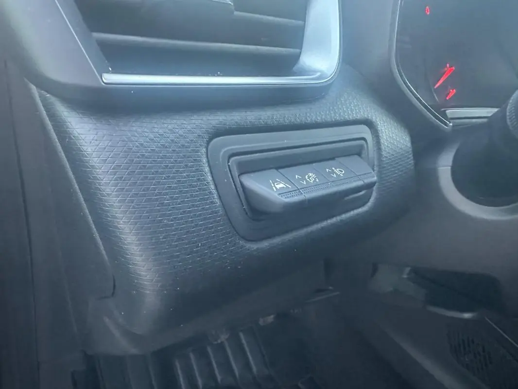 Gros plan sur les commandes d'aide à la conduite à gauche du volant dans l'habitacle sombre d'une Renault Clio gris foncé.