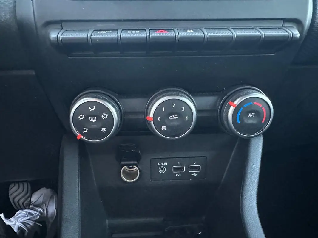 Vue rapprochée des commandes de climatisation manuelle et des ports USB dans une Renault Clio gris foncé 2022.